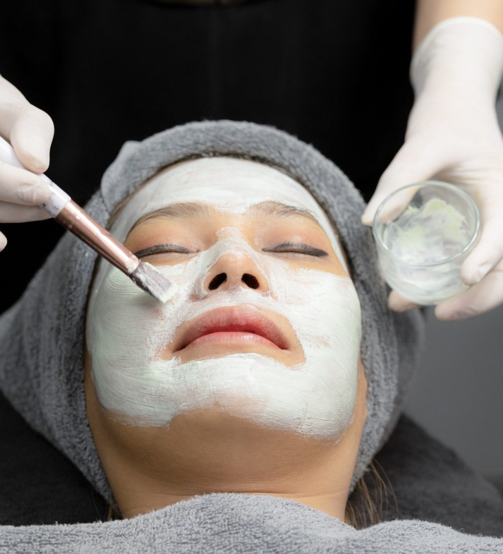 Young woman cream mask facial in beauty clinic.